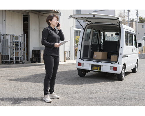 白い軽バンのそばで配送の準備をするドライバー