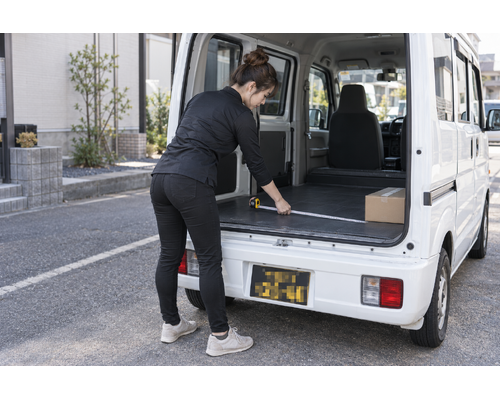 軽バンの荷室の寸法を確認する女性