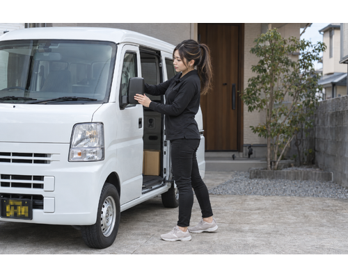 出発前に軽バンのミラーを確認する女性