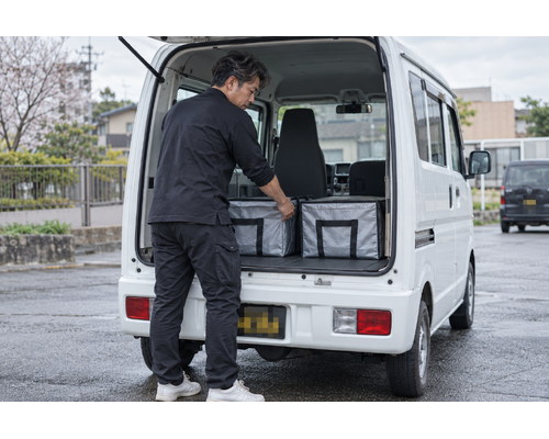 配送用の容器を確認するドライバーと軽バン