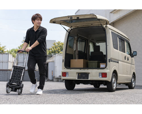 軽バンのそばで台車を準備する男性ドライバー