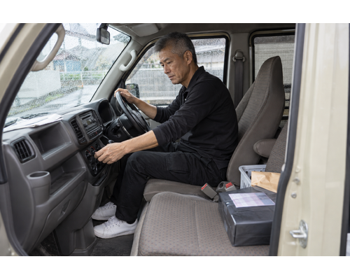 停車した軽バンで空調を調整する男性ドライバー