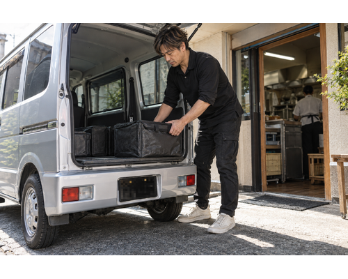お弁当の保冷容器を積み込む男性ドライバー