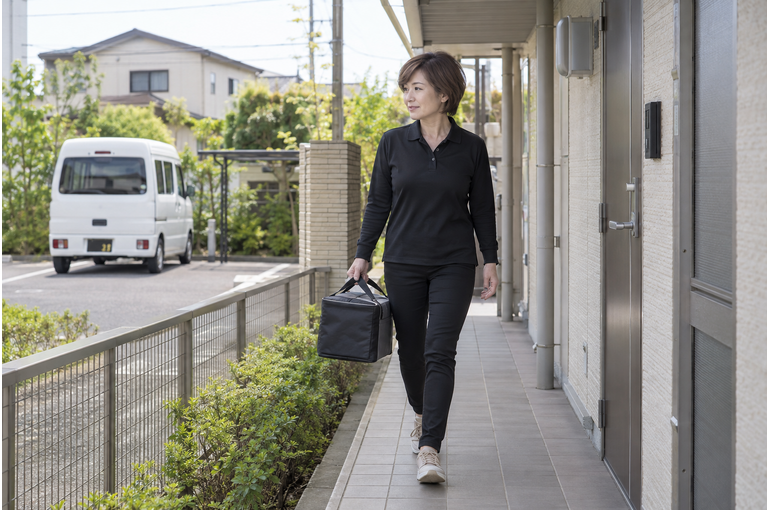 個人宅へお弁当を運ぶ女性