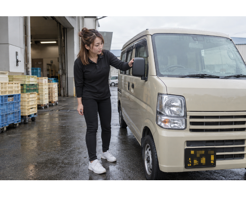 出発前に軽バンのミラーを確認する女性
