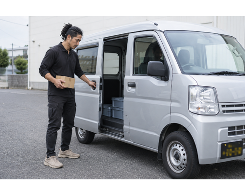 チャーター便の荷物を軽バンへ運ぶ男性