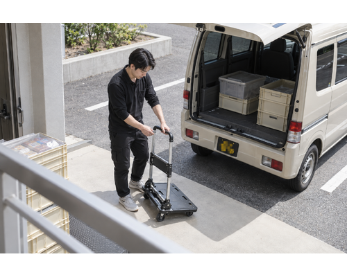 軽バンのそばで台車を広げる男性