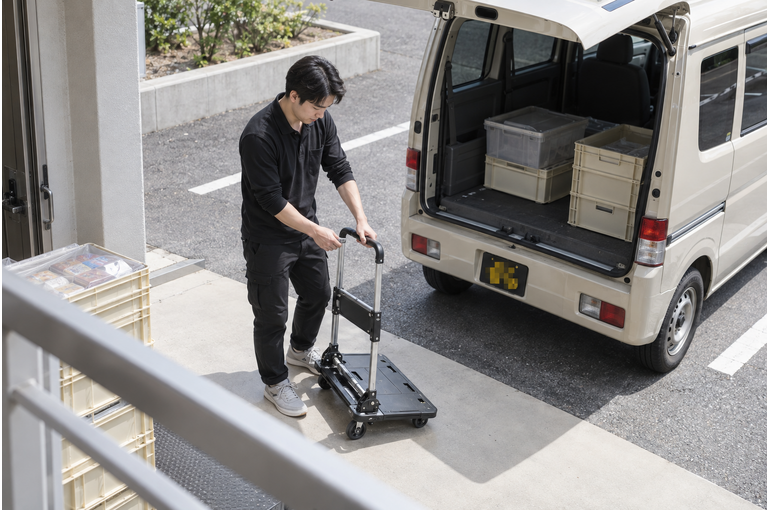 軽バンのそばで台車を広げる男性