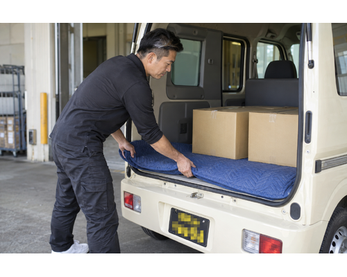 PC関連商品を荷室の保護用マットに載せる男性