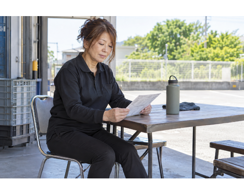 日陰で次の配送予定を確認する女性