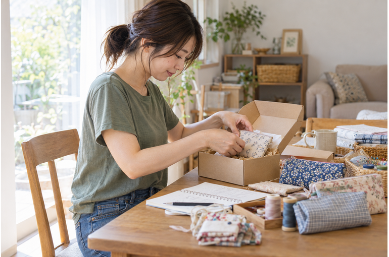 自宅で手作りの布小物を梱包する私服の女性