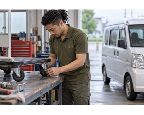 空の台車の車輪を作業台で確認する男性