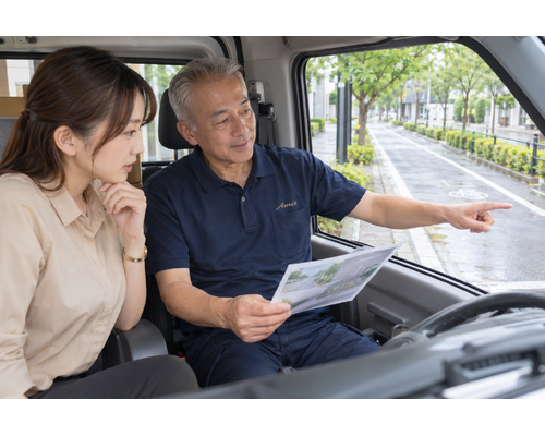 停車した車内で交通ルールの資料を確認する男性