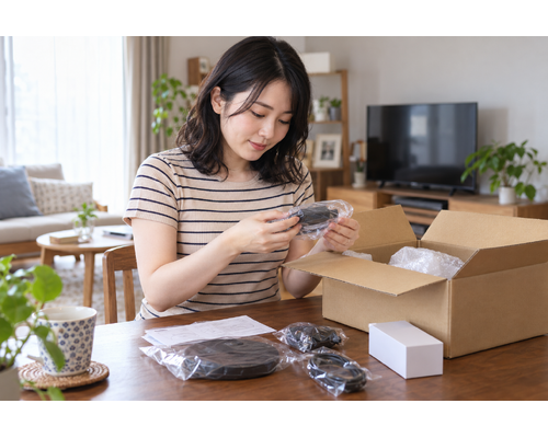 自宅のテーブルで届いた箱の付属品を確認している大人の女性