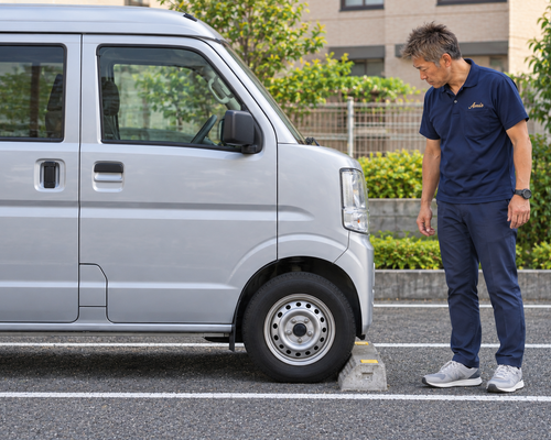 平らな安全な駐車区画で車止めと足元を確認する男性