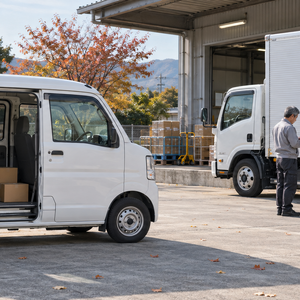 別々に停車した軽バンと2t車のそばで荷物や伝票を確認するスタッフ