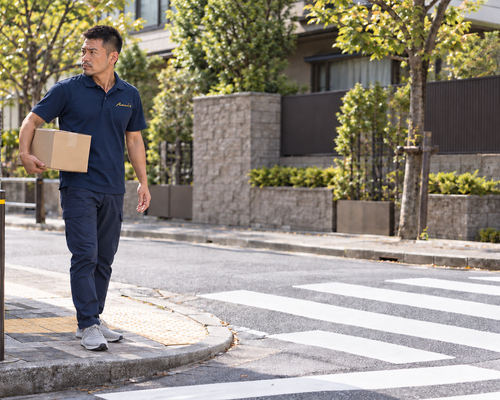 住宅街の横断歩道で周囲の安全を確認する配送ドライバー