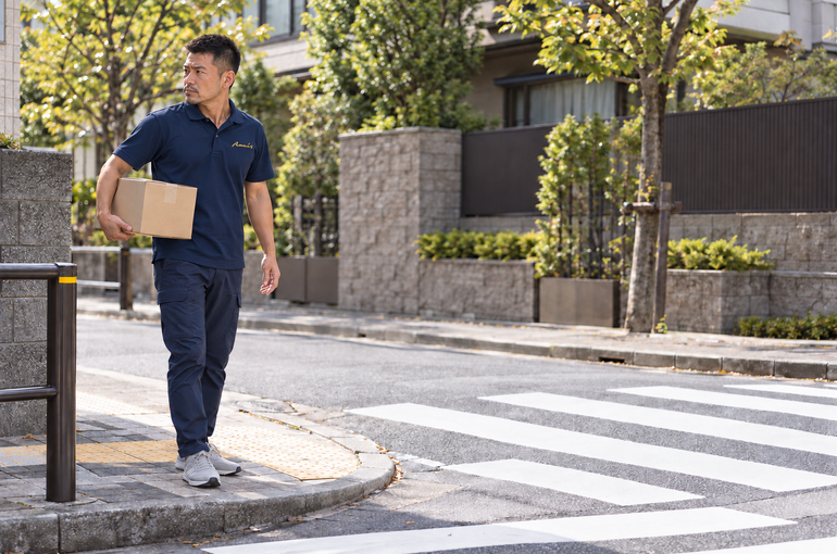 住宅街の横断歩道で周囲の安全を確認する配送ドライバー